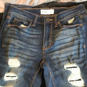 Dark blue jeans with rips that have material covering underneath shown in last